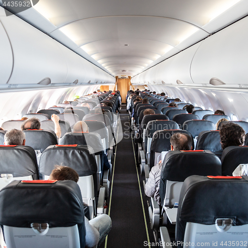 Image of Interior of commercial airplane with passengers on their seats during flight.