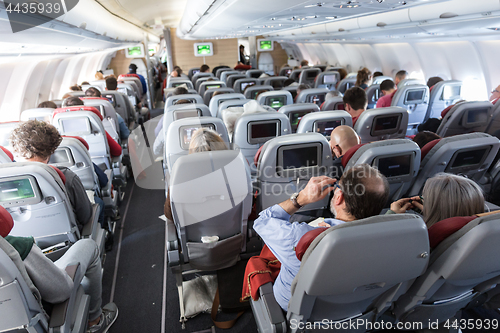 Image of Interior of large commercial airplane with passengers on their seats during flight.