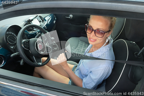 Image of Safety first. Beautiful blonde caucasian lady fastening car seat belt.