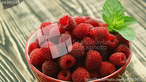 Image of Bowl of raspberry on wooden desk 