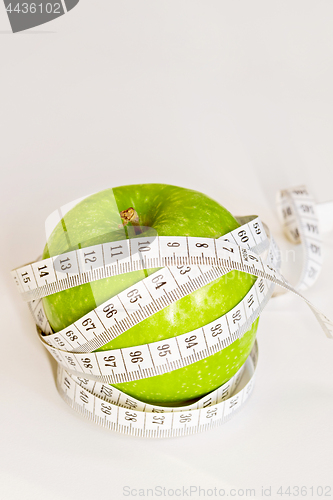 Image of Measuring tape wrapped around a green apple.