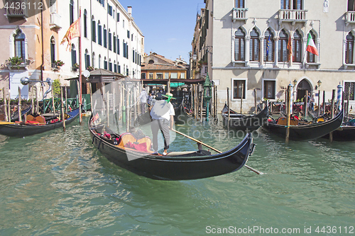 Image of Venetian gondolier in the gondola is transported tourists throug