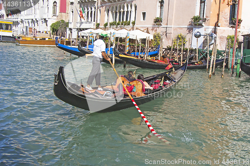 Image of Venetian gondolier in the gondola is transported tourists throug