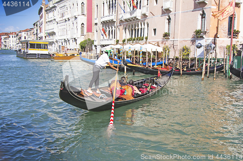 Image of Venetian gondolier in the gondola is transported tourists throug