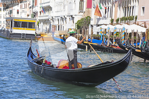 Image of Venetian gondolier in the gondola is transported tourists throug