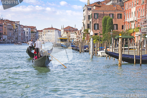 Image of Venetian gondolier in the gondola is transported tourists throug