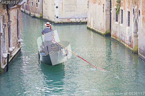 Image of Venetian gondolier in the gondola is transported tourists throug