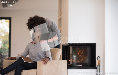 Image of multiethnic couple hugging in front of fireplace