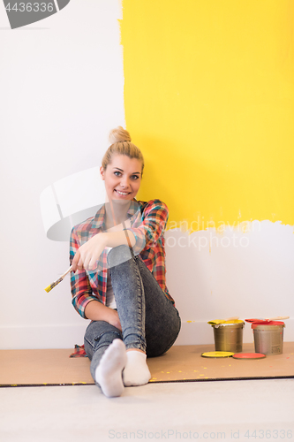 Image of young female painter sitting on floor