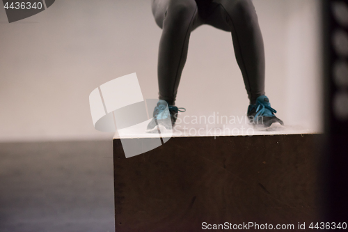 Image of black woman is performing box jumps at gym