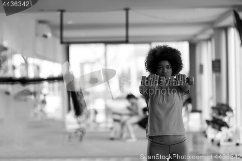 Image of woman working out in a crossfit gym with dumbbells