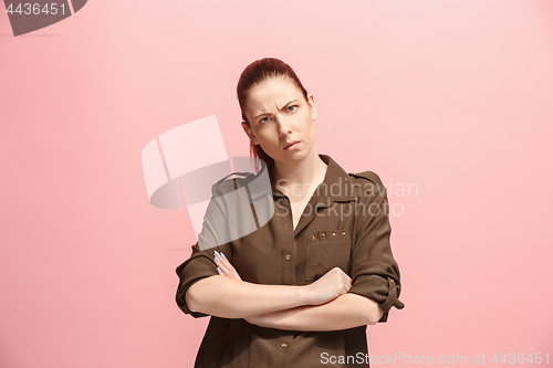 Image of The serious business woman standing and looking at camera against pink background.