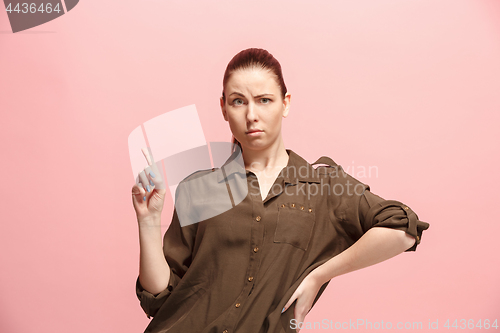 Image of The serious business woman standing and looking at camera against pink background.