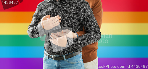 Image of close up of hugging male gay couple over rainbow