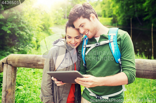 Image of happy couple with backpacks and tablet pc outdoors