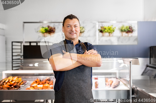 Image of male seller with seafood at fish shop fridge