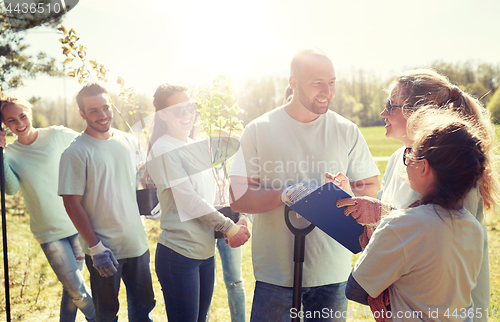 Image of group of volunteers with tree seedlings in park