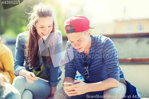 Image of happy teenage friends with smartphones outdoors