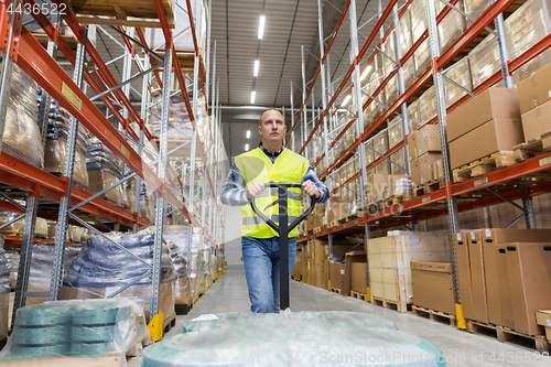 Image of warehouse worker carrying loader with goods