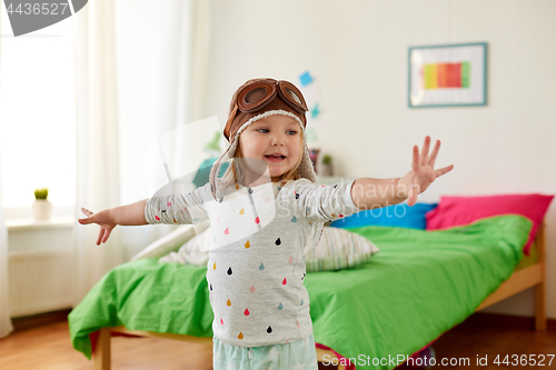 Image of happy little girl in pilot hat playing at home