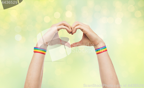 Image of male hands with gay pride wristbands showing heart