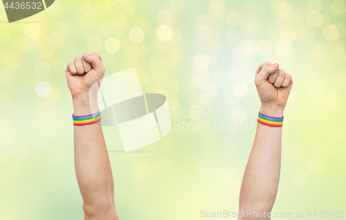 Image of hands with gay pride rainbow wristbands shows fist