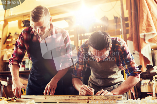 Image of carpenters with ruler and wood plank at workshop