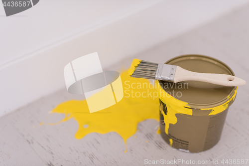 Image of Yellow paint tin can with brush on top