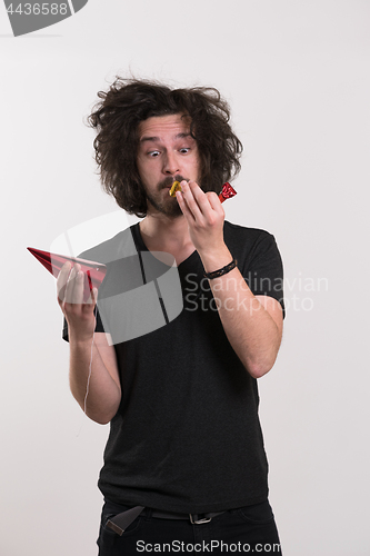 Image of Portrait of a man in party hat blowing in whistle