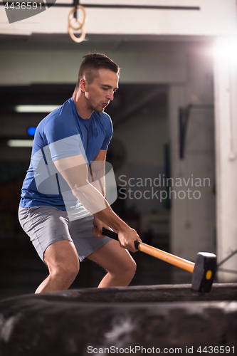 Image of man workout with hammer and tractor tire