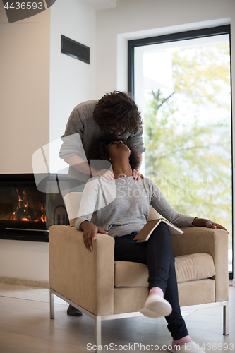 Image of multiethnic couple hugging in front of fireplace