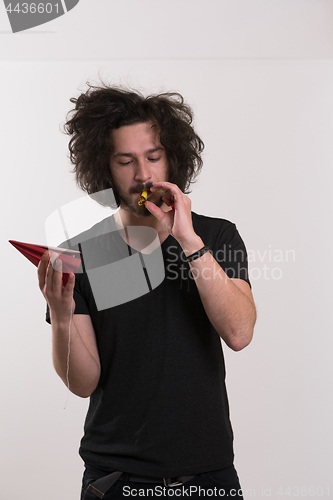 Image of Portrait of a man in party hat blowing in whistle