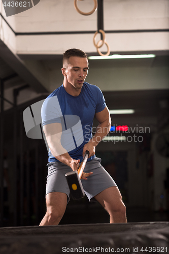 Image of man workout with hammer and tractor tire