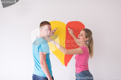 Image of couple are painting a heart on the wall