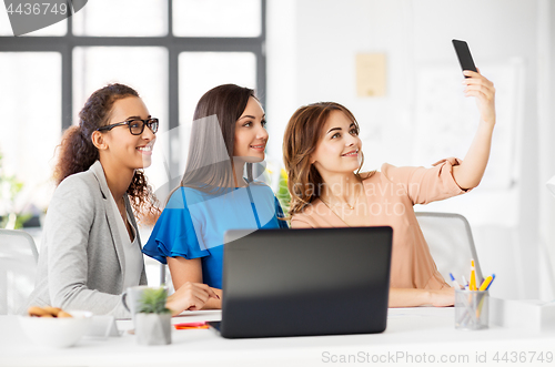 Image of happy businesswomen taking selfie at office