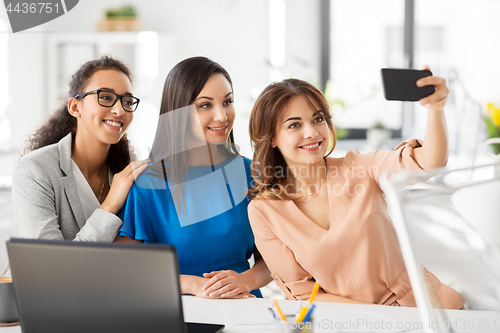 Image of happy businesswomen taking selfie at office