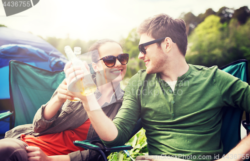 Image of happy couple clinking drinks at campsite tent