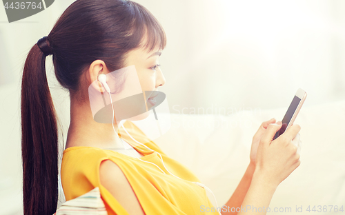 Image of happy asian woman with smartphone and earphones