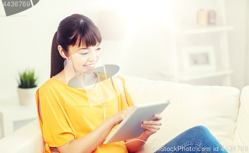 Image of happy asian woman with tablet pc and earphones