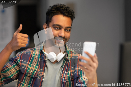 Image of man with smartphone having video call at office