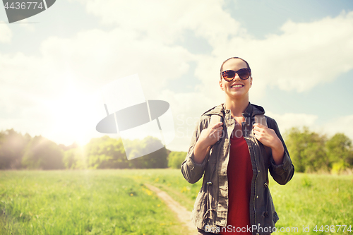 Image of happy young woman with backpack hiking outdoors
