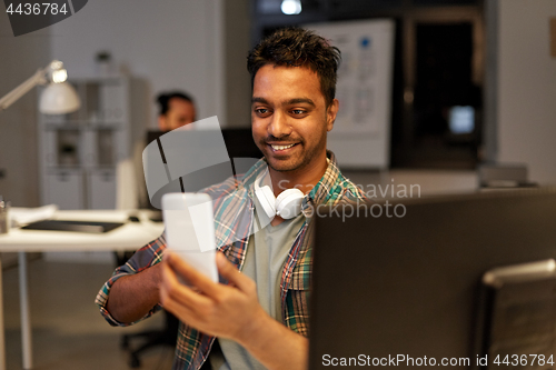 Image of man with smartphone having video call at office