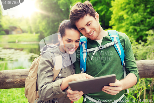 Image of happy couple with backpacks and tablet pc outdoors