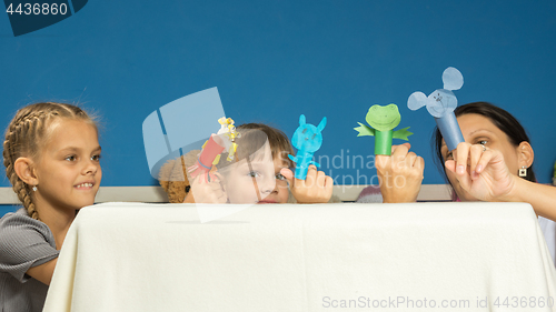 Image of Mom and daughters show a performance in a fingered self-made puppet theater