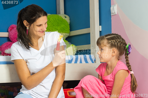 Image of Mom put a figure of colored paper on her finger and shows her daughter