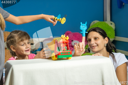 Image of An enthusiastic mother plays with daughters in a self-made finger puppet theater