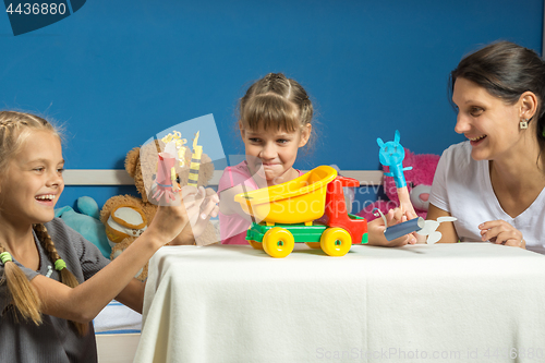 Image of Mom plays with two daughters in a self-made finger puppet theater