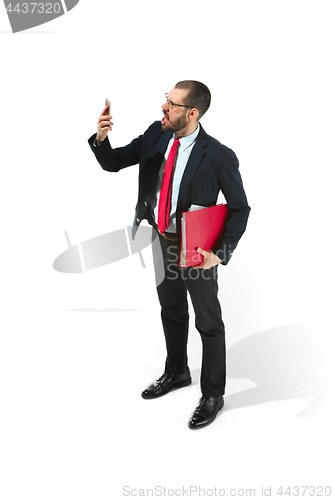 Image of Angry businessman talking on the phone with folder in hand isolated over white background in studio shooting