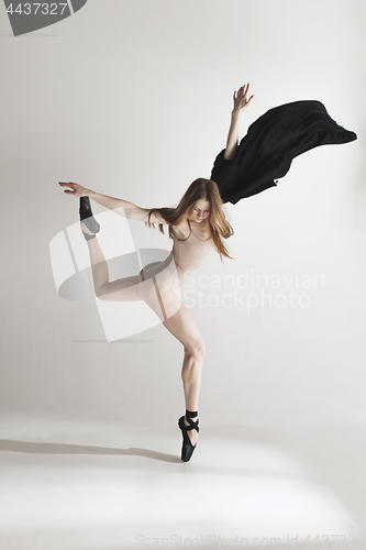 Image of Young beautiful dancer in beige swimsuit dancing on gray background