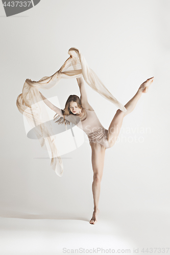 Image of Young beautiful dancer in beige swimsuit dancing on gray background